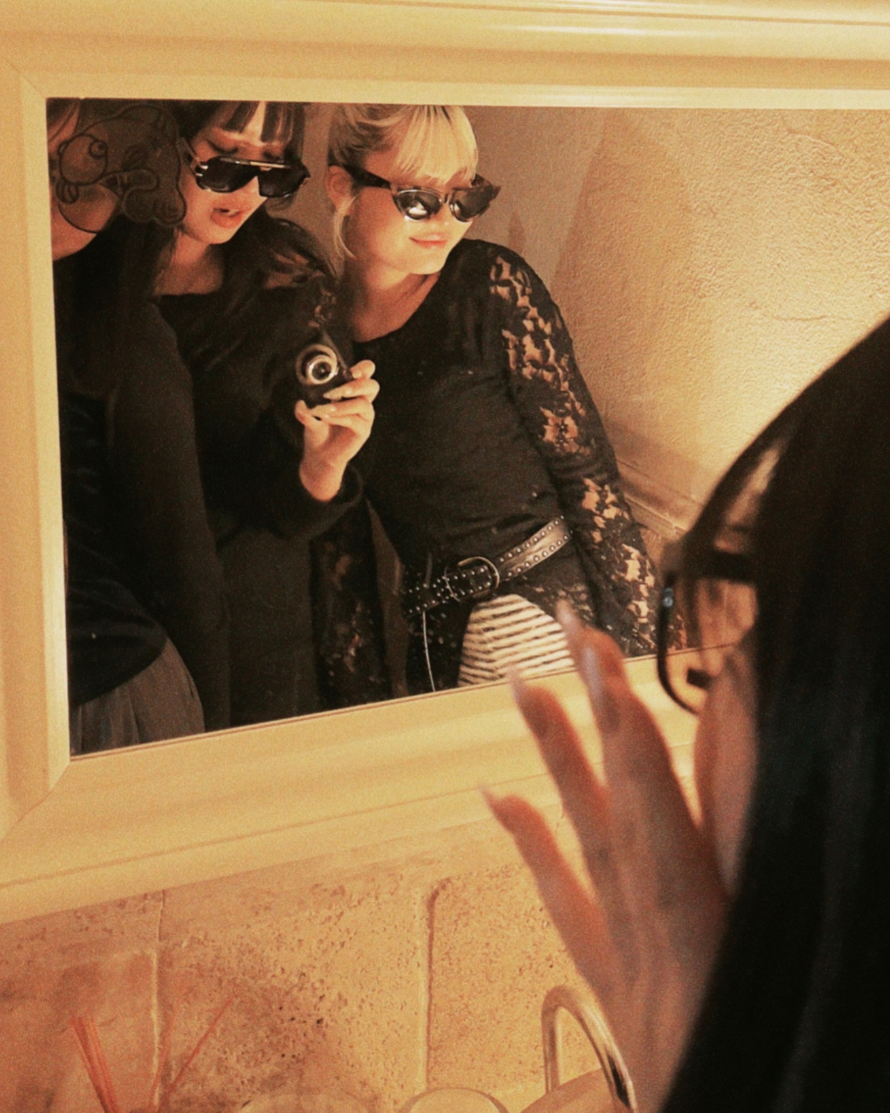 Person taking a mirror selfie wearing sunglasses and a patterned jacket.