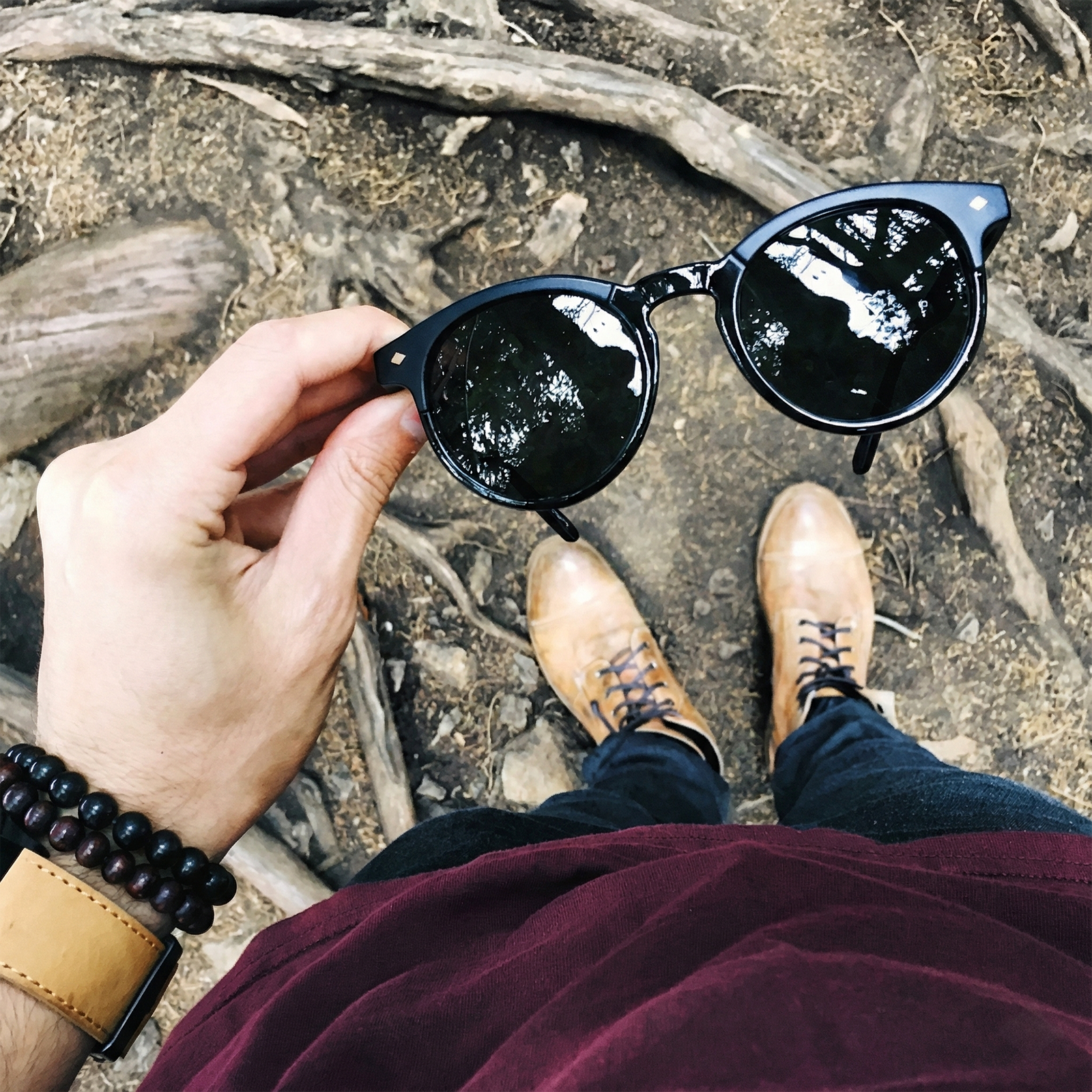 Person holding black sunglasses with a natural background