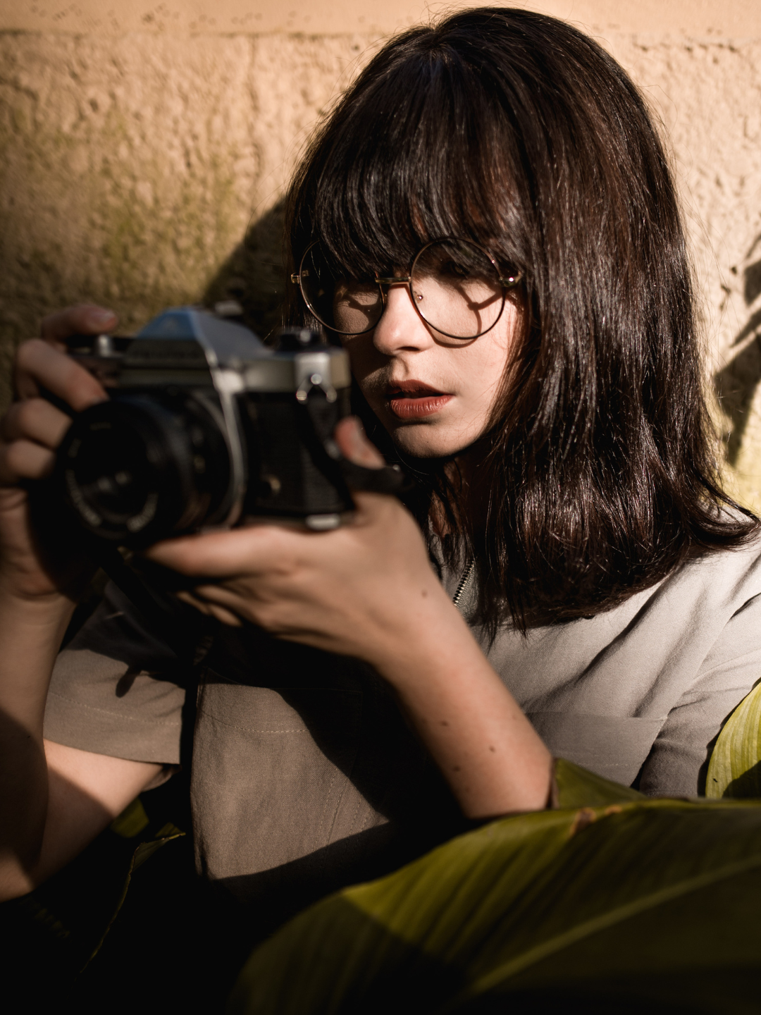 Person holding a camera against a textured wall