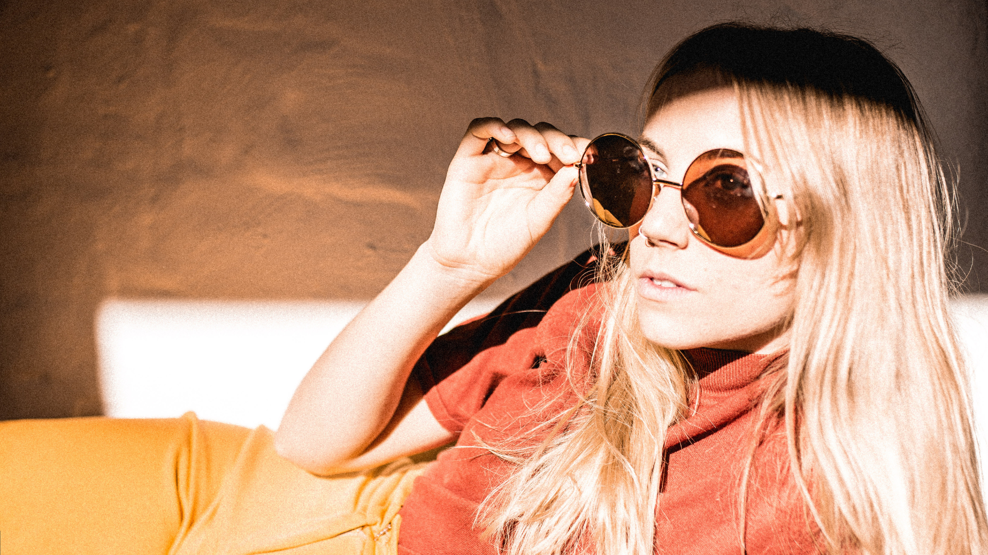 Woman wearing sunglasses with a warm, blurred background