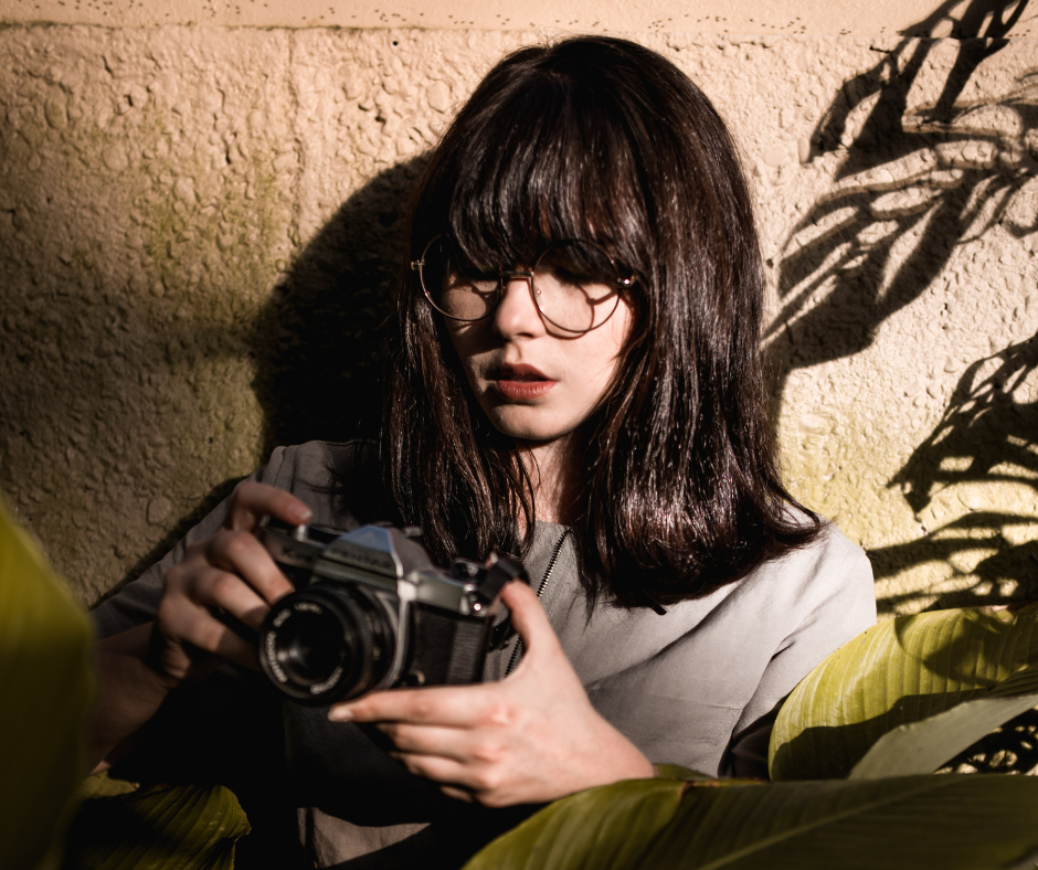 Person holding a camera against a textured wall with shadows