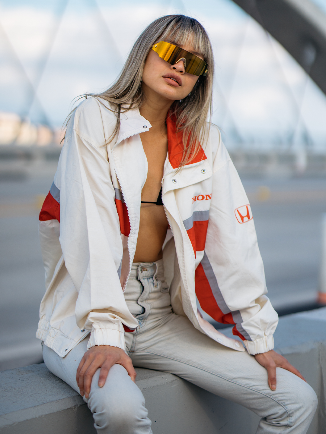 Person wearing a white jacket with red and gray accents, sitting outdoors.